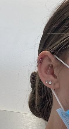 a close up of a person wearing ear wires and an earring on their head