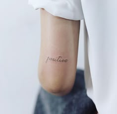 a woman's foot with the word positive tattooed on her left leg, in black ink