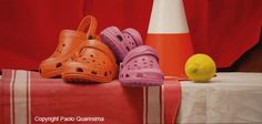 three pairs of crocs sitting on top of a table next to a lemon