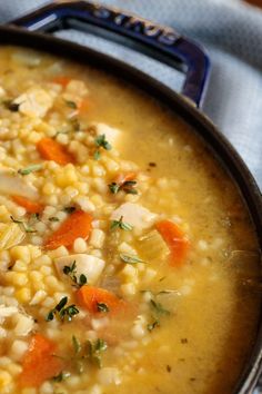 a bowl filled with corn and carrots on top of a blue table cloth next to a spoon