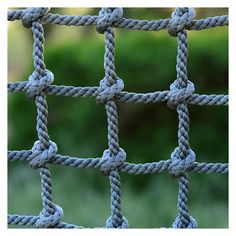 a close up view of a rope fence with green grass in the backround