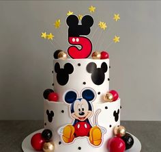 a mickey mouse birthday cake with gold stars and decorations on the top, sitting on a table