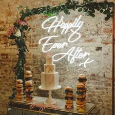 a wedding cake and macaroons sitting on a table in front of a sign that says happily ever after