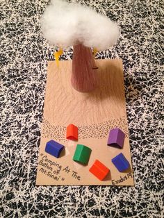 a wooden toy with colored blocks and a cloud on it's head sitting on top of a piece of paper