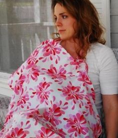 a woman sitting on a couch with a pink and white flowered blanket draped over her