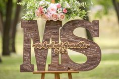 a wooden sign with the word mss written on it and flowers in front of it