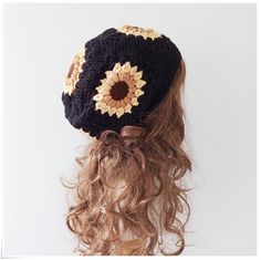 a woman with curly hair wearing a crochet sunflower hat on top of her head