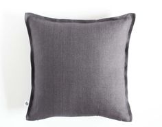 a dark gray pillow sitting on top of a white wall