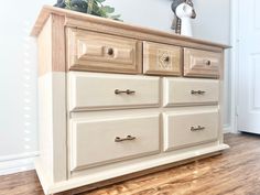 a white dresser with wooden drawers in a room