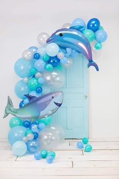 a dolphin balloon arch with blue and white balloons on the floor next to a door