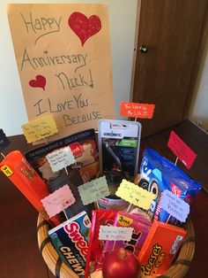 a basket filled with lots of different items on top of a wooden table next to a sign that says happy anniversary nick i love you because