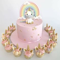 a pink unicorn cake with cupcakes on it and an instagramr above