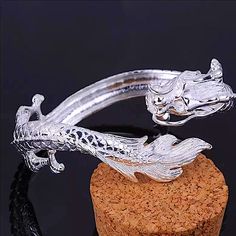 a silver dragon bracelet on top of a rock