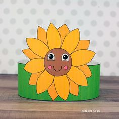 a paper sunflower on top of a green box with polka dot wall in the background