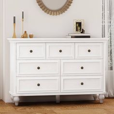 a white dresser with gold accents and a round mirror on the wall above it in a room