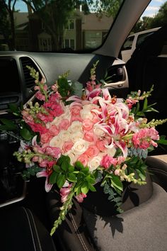 a bouquet of pink and white flowers sitting in the back seat of a car,