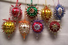 twelve christmas ornaments are hanging on a white wall with beads and bows attached to them