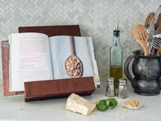 an open book sitting on top of a counter next to utensils and other kitchen items