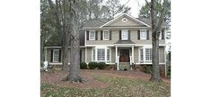 a house in the woods with lots of trees and leaves on the ground around it