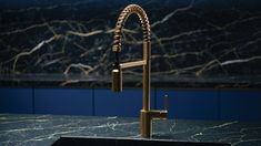 a kitchen sink and faucet in front of a marble counter with blue walls