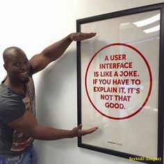 a man pointing at a sign on the wall that says, a user interface is like a joke if you have to explain it, it's not that good