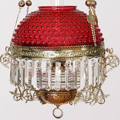 a red and gold chandelier hanging from a ceiling fixture with beads on it