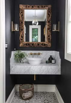 a white sink sitting under a mirror next to a bathroom vanity with a gold framed mirror above it