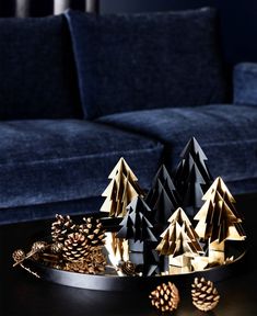 some pine cones are sitting on a tray next to a couch and christmas tree decorations