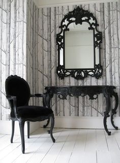 a chair sitting next to a mirror on top of a wooden table in front of a wall