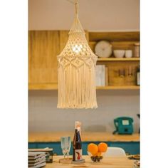 a chandelier hanging from the ceiling over a table with oranges and bottles on it