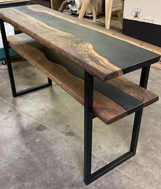 a wooden bench sitting on top of a cement floor next to a piece of wood