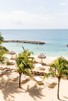 the beach is lined with palm trees and umbrellas