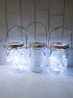 three mason jars with lids and wire handles