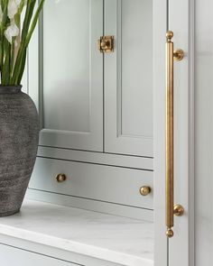 a vase filled with flowers sitting on top of a white counter next to a cabinet