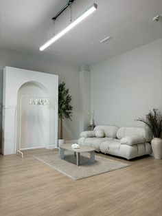 a living room with white furniture and wood flooring on the wooden floor is an arch in the wall