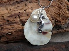 a necklace with a seahorse on it and a pearl bead hanging from the end