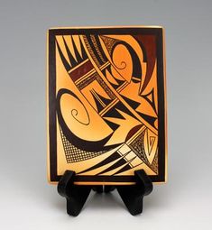 an orange and black plate with abstract designs on the front, sitting on a stand