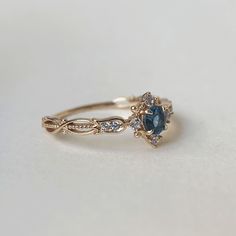 a gold ring with blue and white stones on it's side, sitting on a table