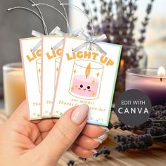 someone holding up two cards with candles in the background and some lavenders around them