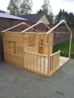 a small wooden house sitting on top of a brick floor next to a fenced in yard