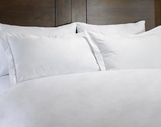 a bed with white sheets and pillows on it