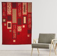 a chair sitting in front of a red wall hanging