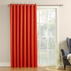 an orange curtain hangs in front of a window with a blue chair next to it