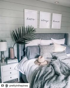 a bed with pillows and blankets on it in a bedroom next to two framed pictures