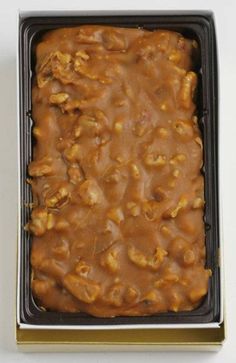 a box filled with lots of food on top of a white table next to a knife