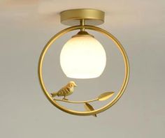 a bird is perched on the end of a light fixture with a white ball hanging from it's center