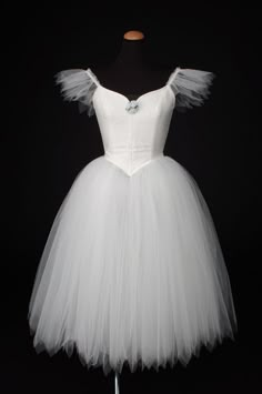 a white tutule dress on a mannequin head stand in front of a black background