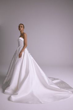 a woman in a white wedding dress is posing for a photo with her hands on her hips