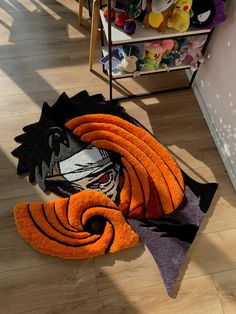 an orange and black towel laying on the floor in front of a shelf filled with stuffed animals