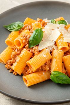 a plate with pasta and meat on it, garnished with parmesan cheese